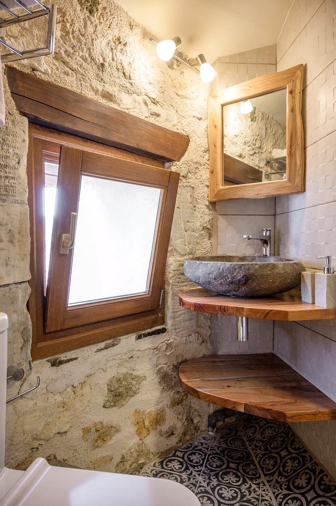 Bathroom with stone vessel sink on live-edge wood shelf