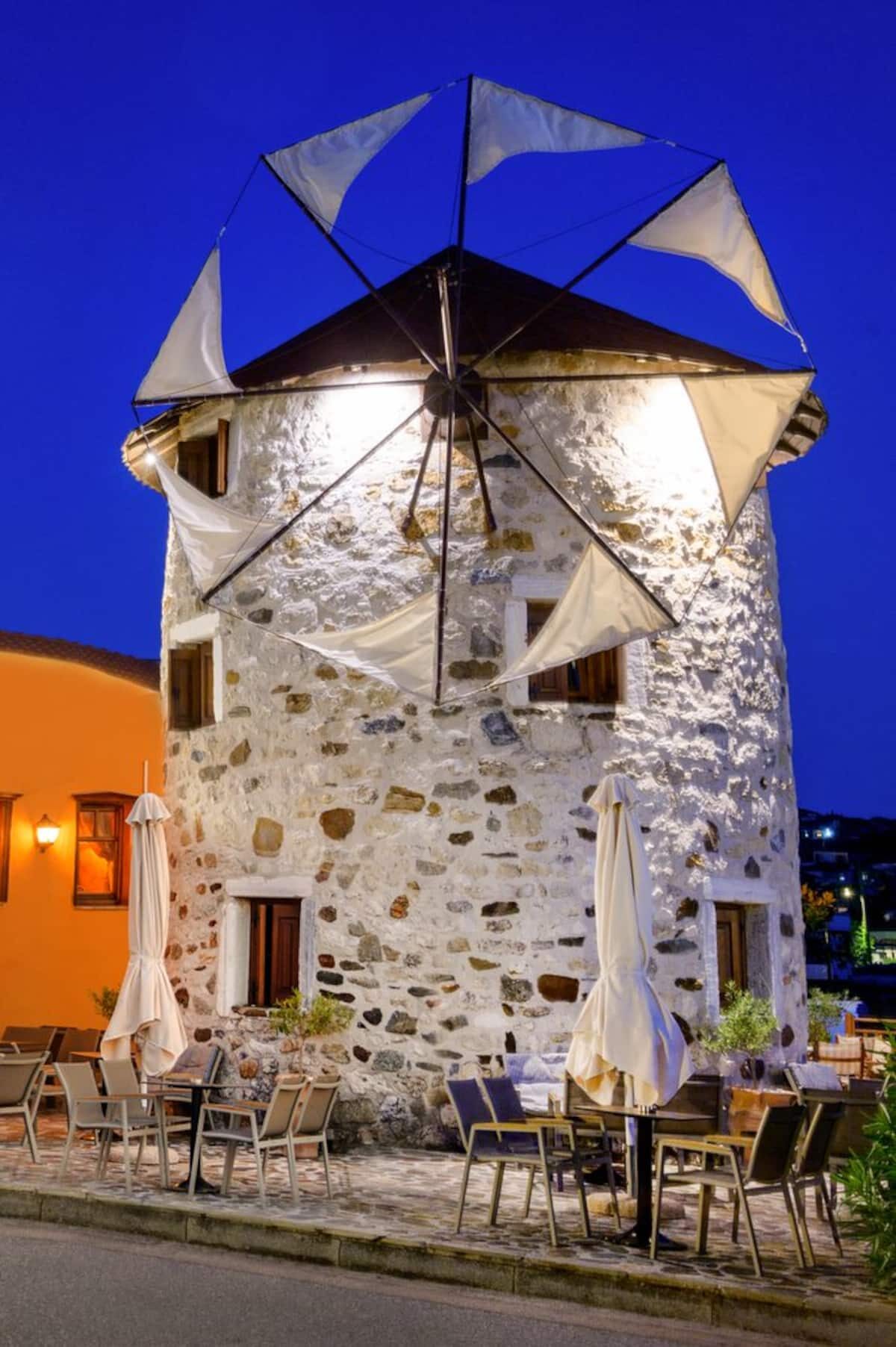 The Windmill in Ierissos at twilight, lit against a deep blue sky